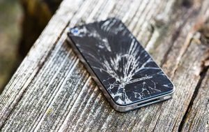 Handy-Reparatur: Smartphone mit kaputtem Display liegt auf Holz
